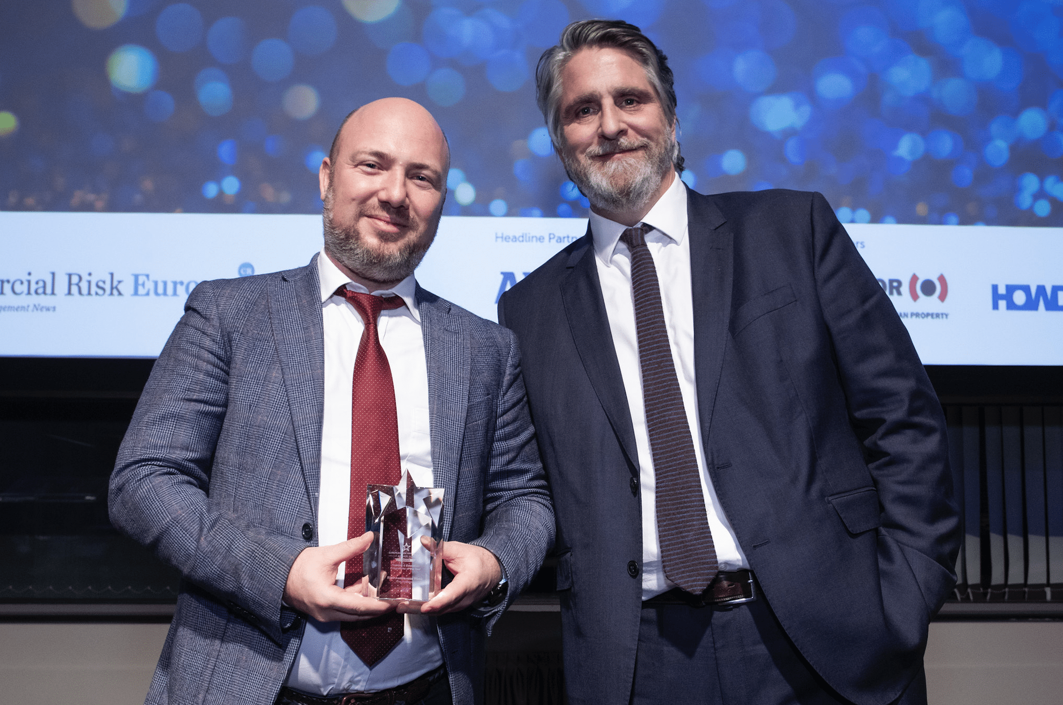 Vom Praktiker zum Pionier: Alex Sidorenko (li.) neben Hugo Foster vom Commercial Risk Magazine. Der Preis geht an das Schulungs- und Ausbildungsprogramm des Jahres 2024, FERMA.